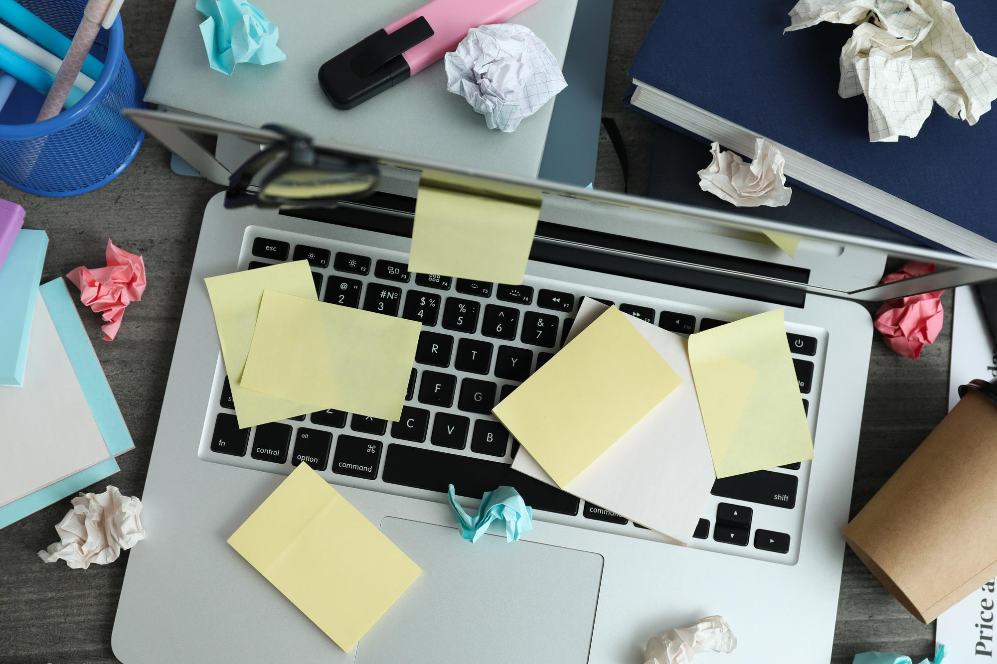 Unordentlicher Büroarbeitsplatz mit einem Laptop und vielen geklebten und zerknüllten PostIt's