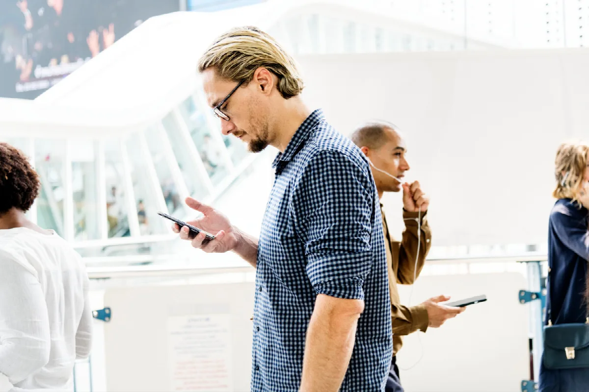 Ein Blonder Mann, der auf seinem Telefon eine SMS schreibt.